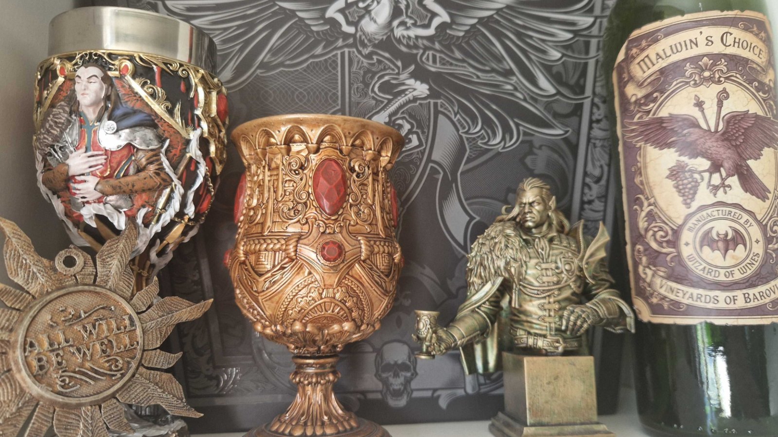 Curse of Strahd props on a white shelf including a goblet, sun, bust, and wine bottle